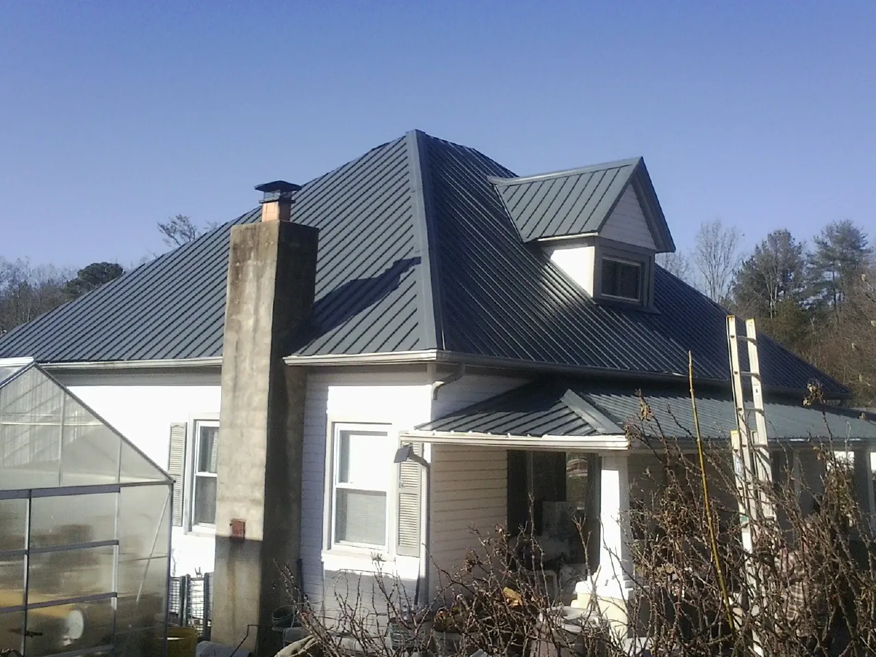 Dark blue standing seam metal roof on a white farmhouse with dormer — Slate & Tile Roof Repair by Roofing Brothers in Weed