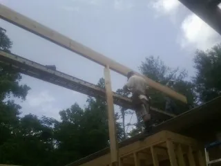 Carpenter setting a ridge beam over a new addition frame — Ice Dam Removal by Roofing Brothers in Weed