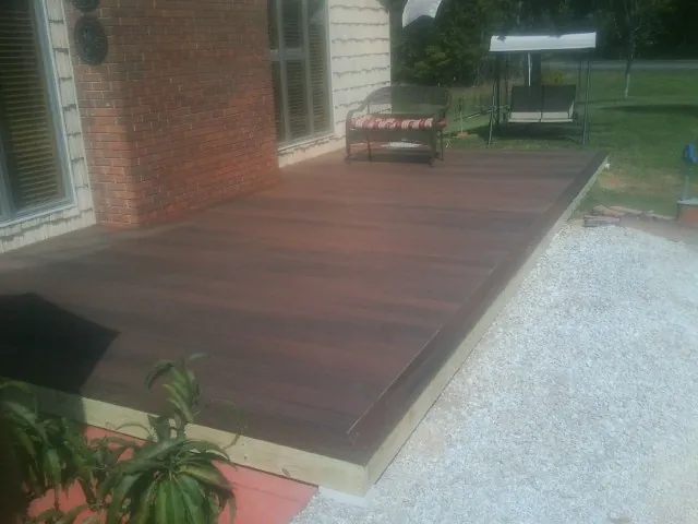 Freshly stained wood deck built against a brick home in Weed