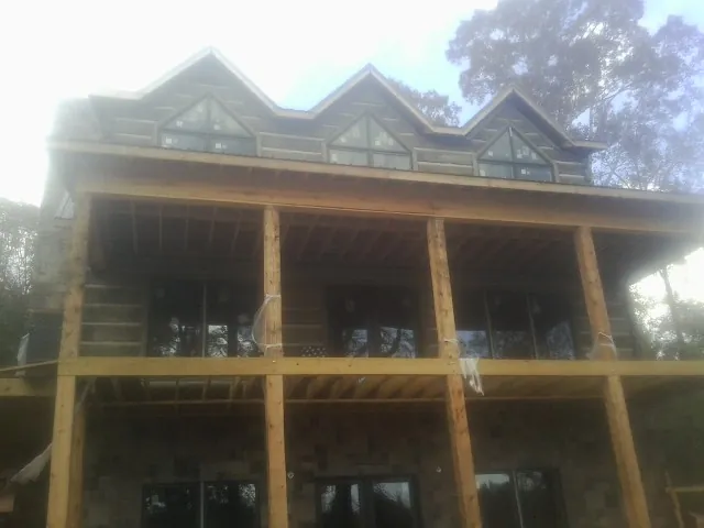 Dormers and porch framing on a large log home under construction — Roof Coating work by our crew in Weed