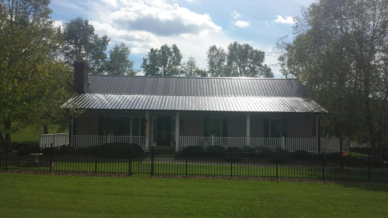 Gray metal roof on a brick ranch with a full width front porch — Gutter Guard Installation work by our crew in Weed