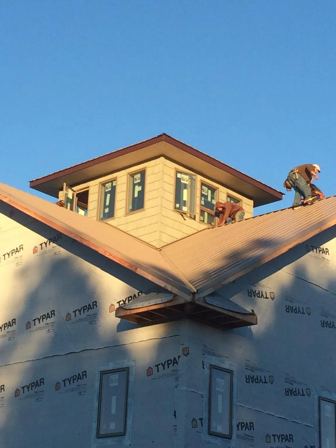 Roofers working around a rooftop cupola on a new metal roof at sunset — Roof Waterproofing in Weed by Roofing Brothers